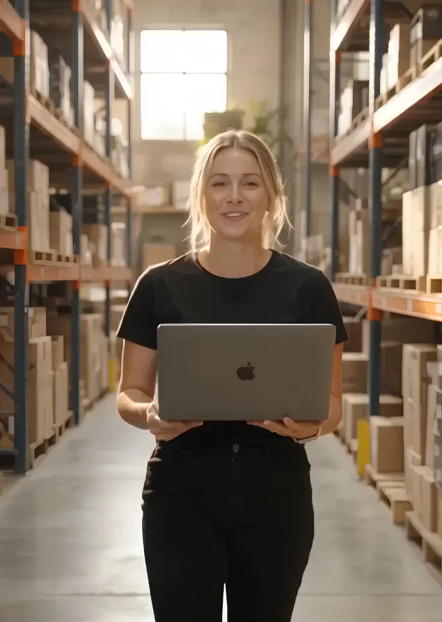 A Tracksy teammate walking the warehouse aisle with a laptop